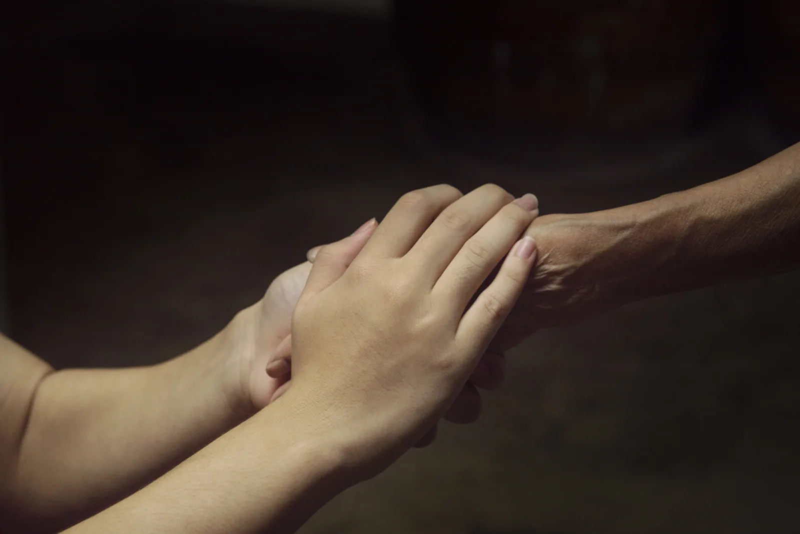 A younger hand holding an older hand in support